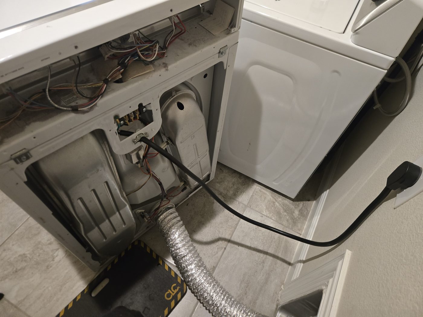 Rear of a dryer pulled from the wall showing the vent connection