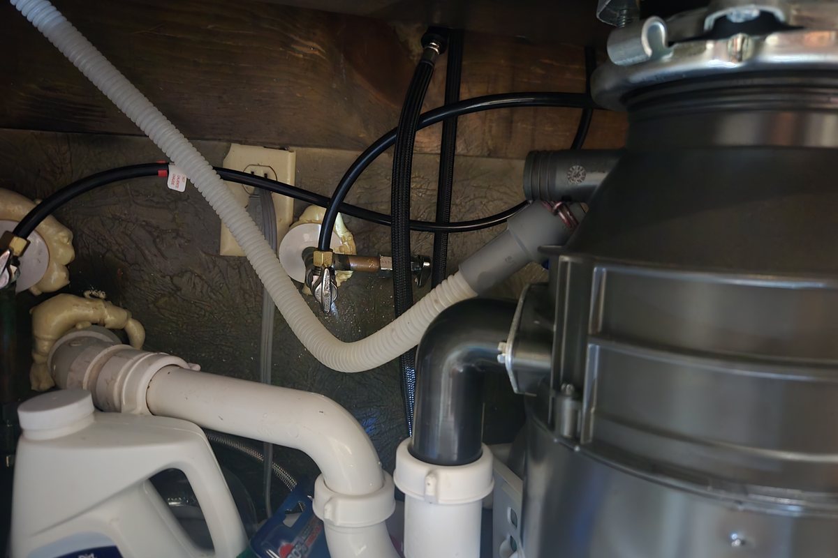 Under-sink dishwasher drain and disposal plumbing inspected during a service call