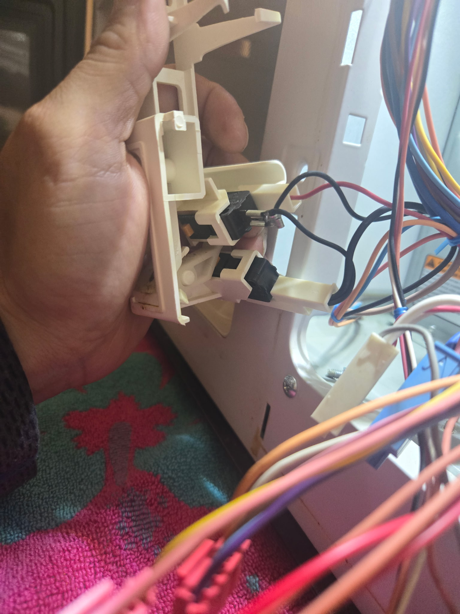 Technician holding a failed door latch assembly removed from an appliance
